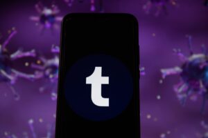 Photo illustration of a Tumblr logo displayed on a smartphone with a COVID 19 sample image in the background.